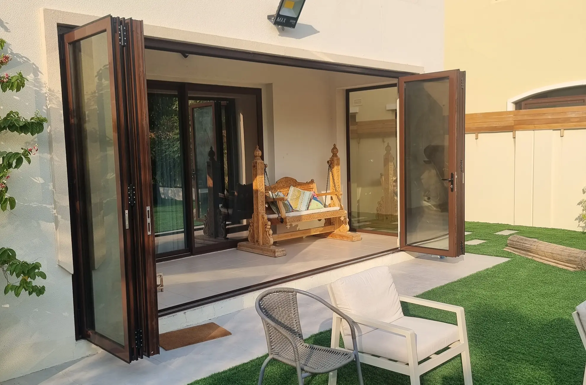 Modern aluminium bi-fold doors with large glass panels opening to a garden terrace in Dubai.