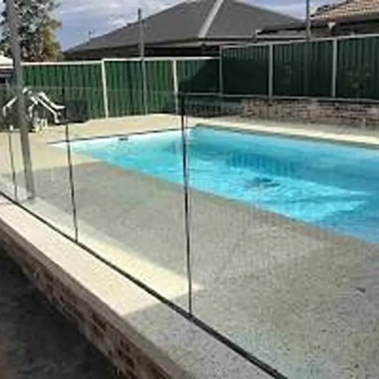 Minimalist pool glass fence using recessed aluminium U-channel for an invisible floor finish.