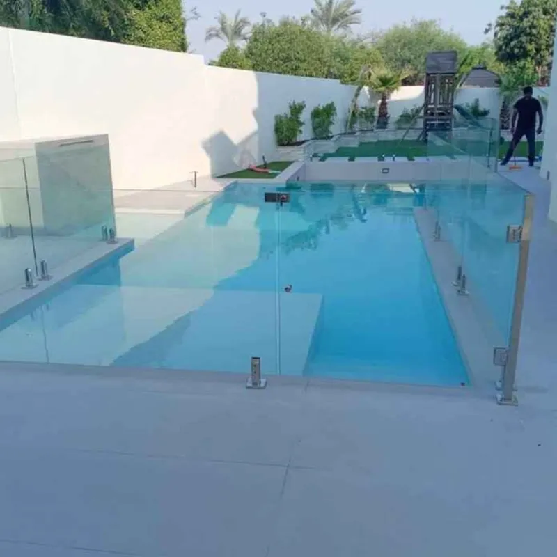 Modern frameless glass pool fencing with stainless steel spigots for a residential villa garden in Dubai.