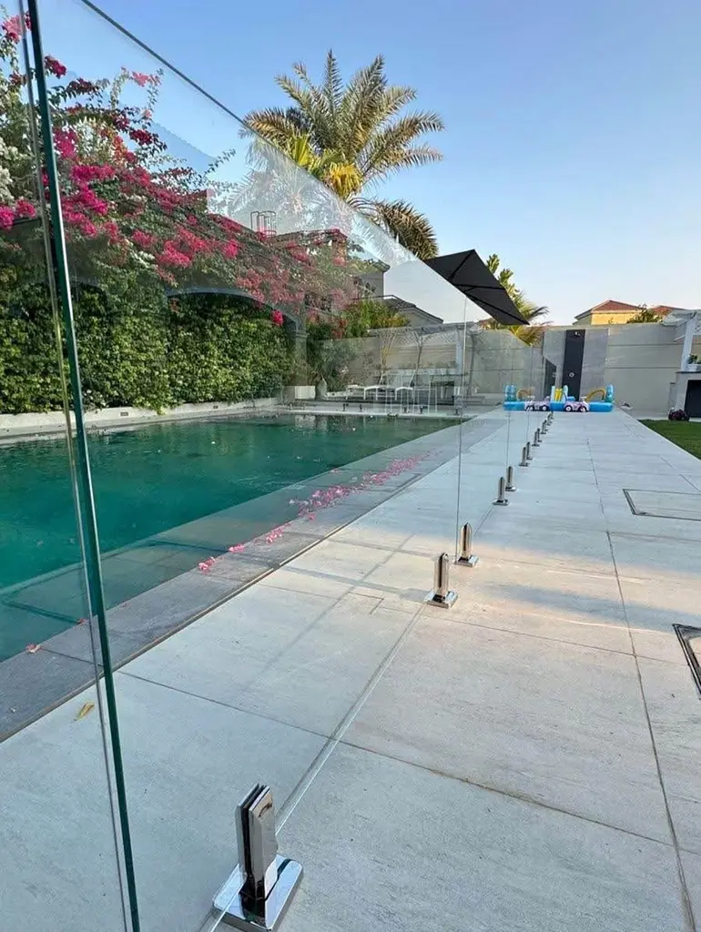 Safety-certified frameless glass swimming pool fence with stainless steel spigots for luxury backyards.