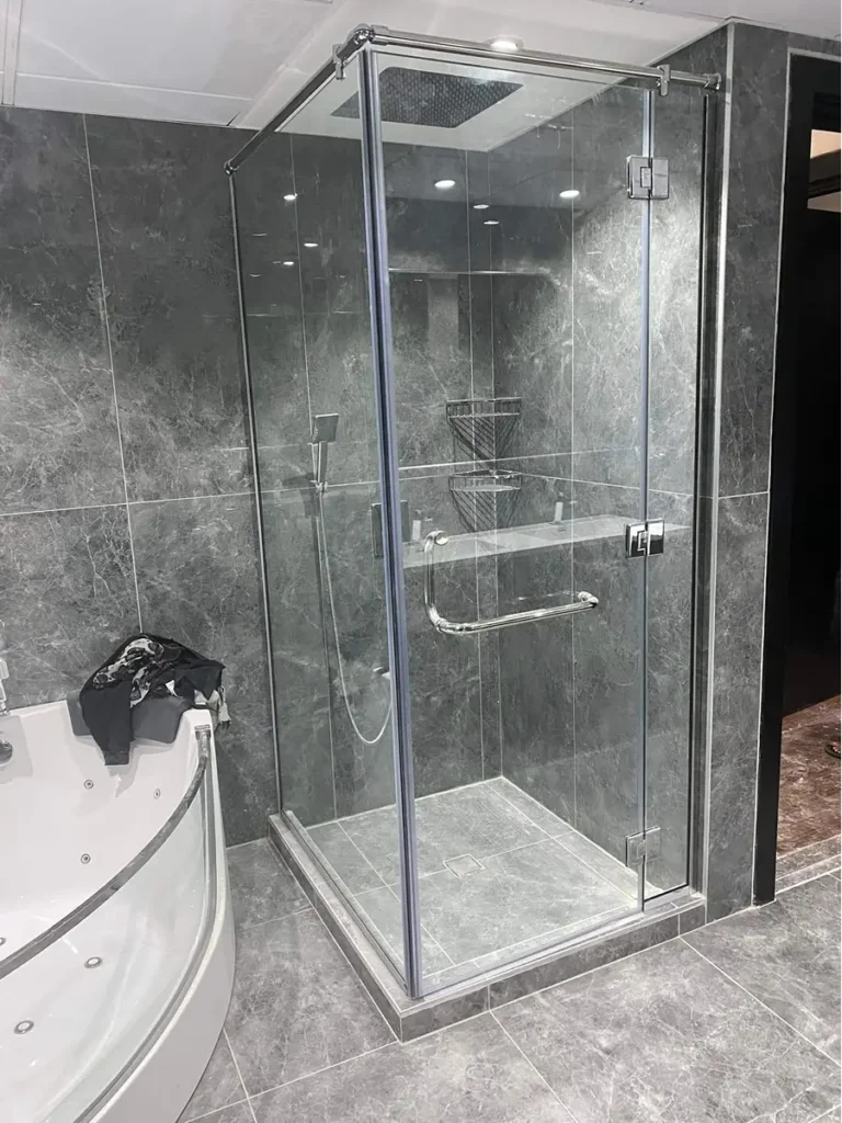 Tempered glass shower enclosure with chrome hardware and sliding door.