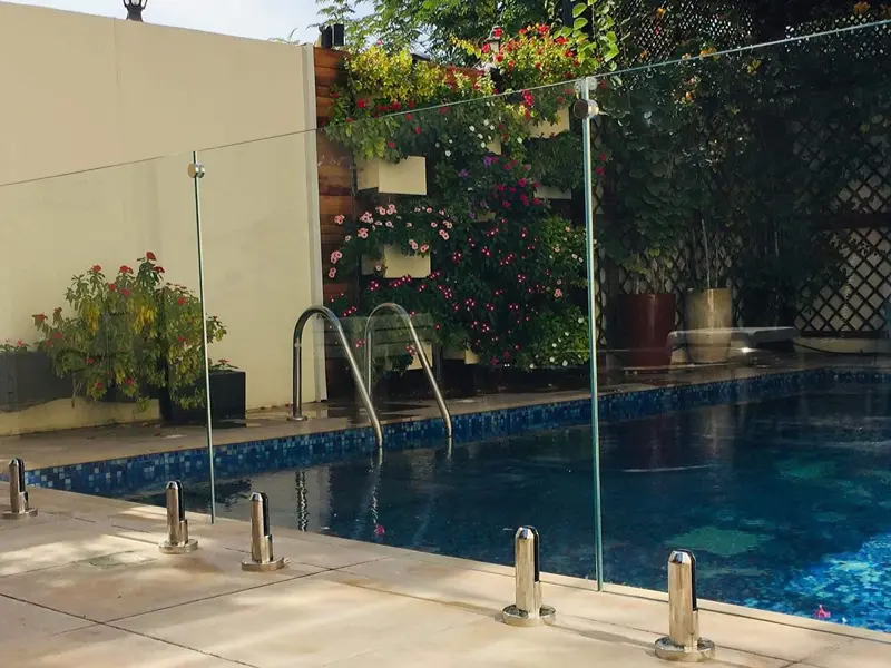 Frameless tempered glass pool fence with stainless steel spigots for villa safety.