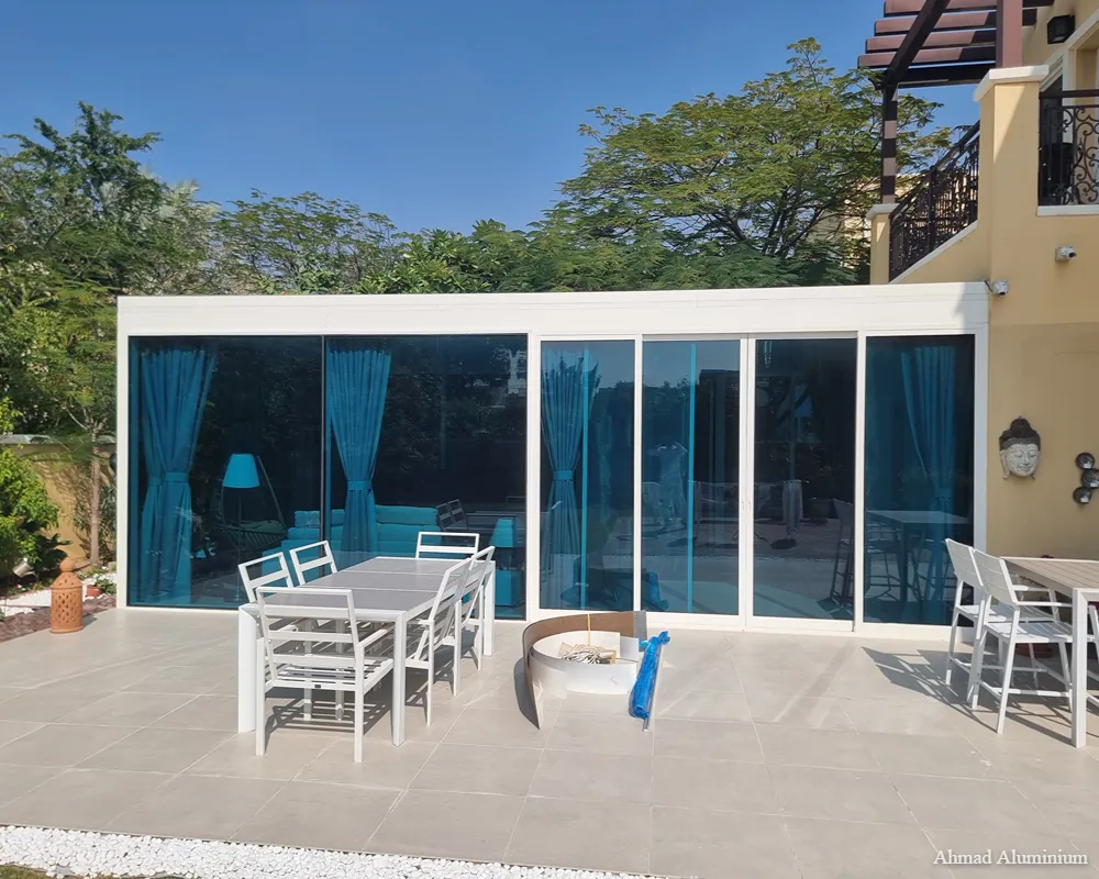 Luxury sunroom extension with tempered glass roof and black aluminium frames for a Dubai villa.