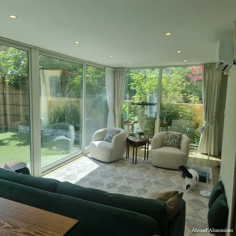 Luxury living room glass extension with slim black aluminium frames and panoramic garden views.