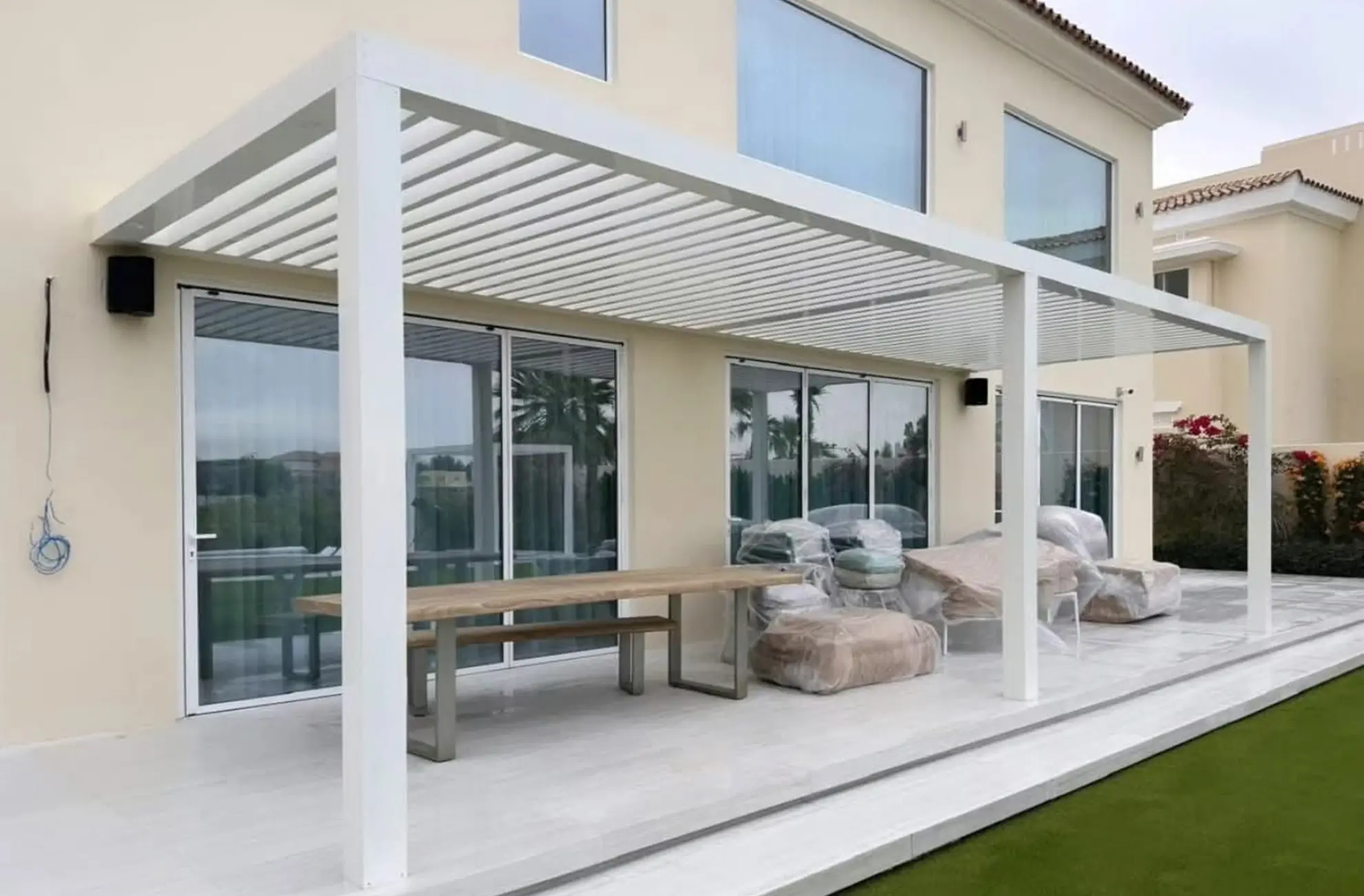 Custom white louvered aluminium pergola for outdoor garden terrace and sun protection.