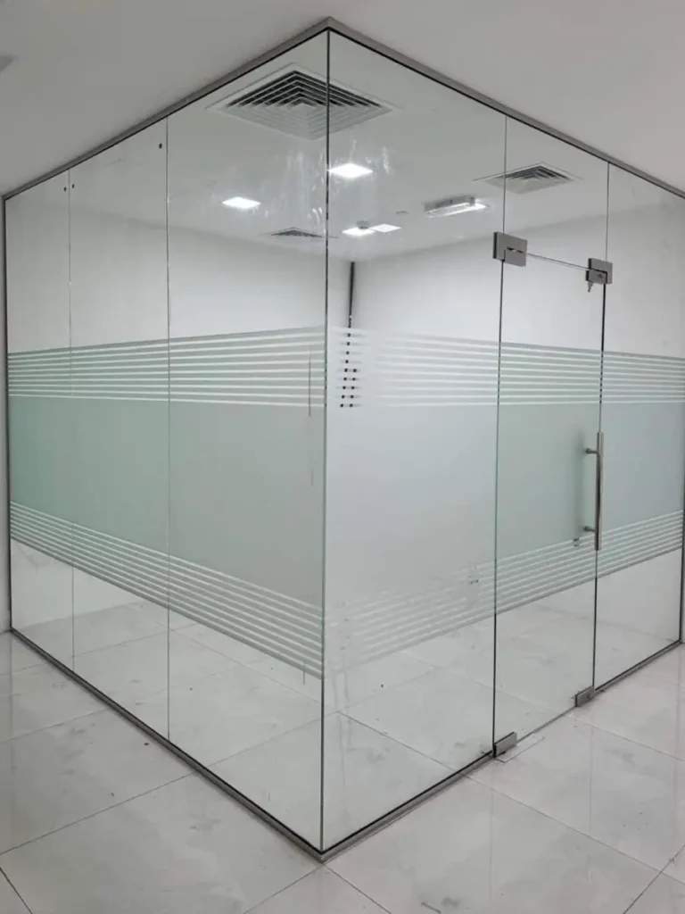 Frameless office glass partition with black aluminium tracks and door.