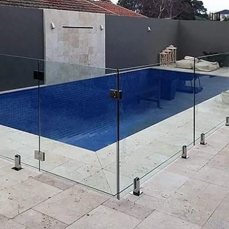 Side-mounted glass pool fence with stainless steel standoff pins fixed to a concrete boundary wall.